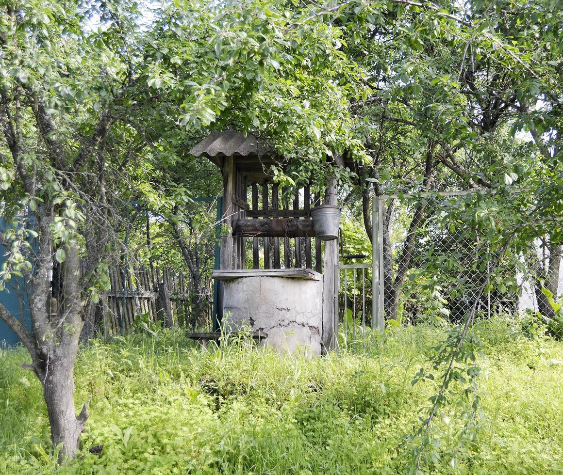 Old well with iron bucket on long forged chain photo