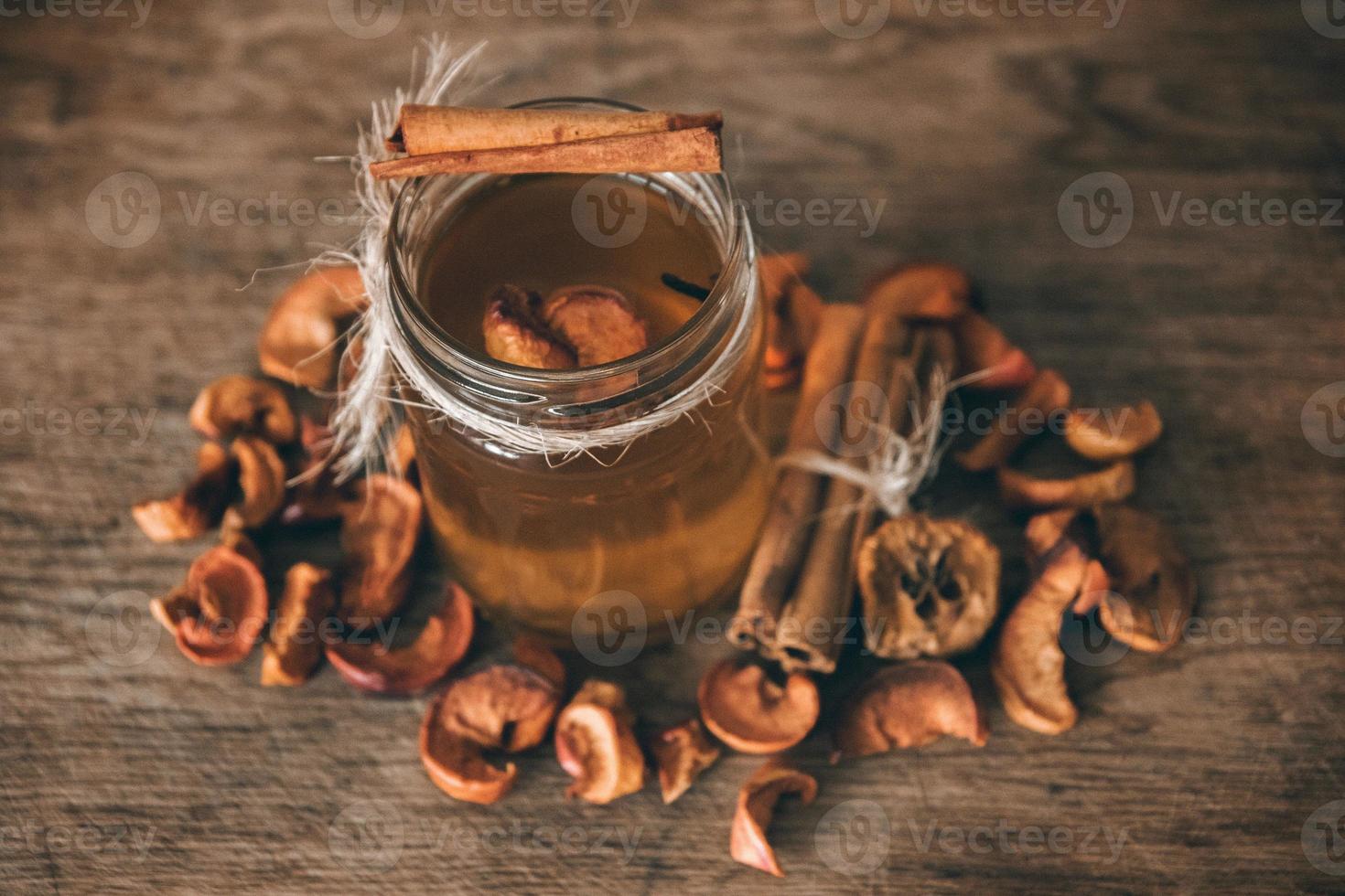 Fruit compote of dried apples in a glass jar on a wooden rusric board photo