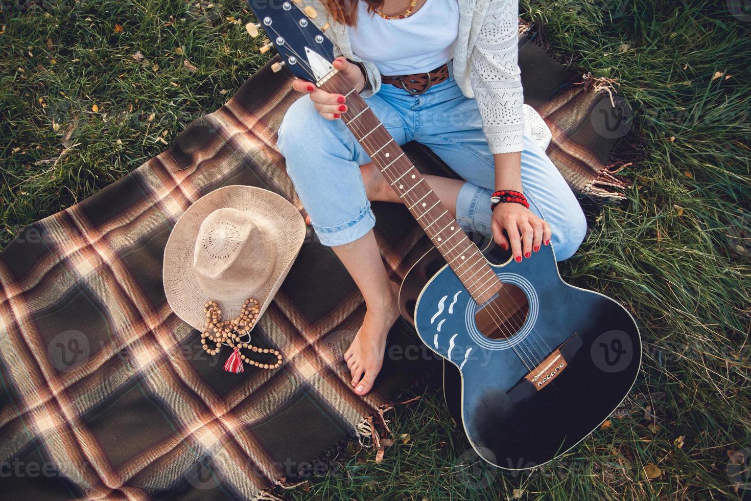 Bella mujer con guitarra descansando sobre césped verde foto