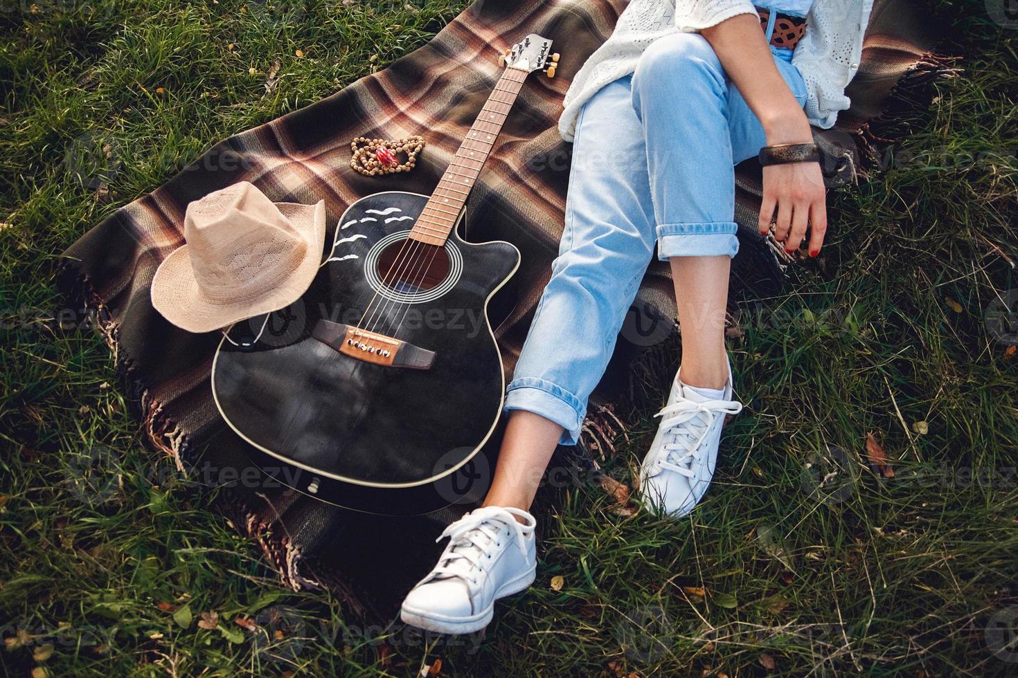 Bella mujer con guitarra descansando sobre césped verde foto