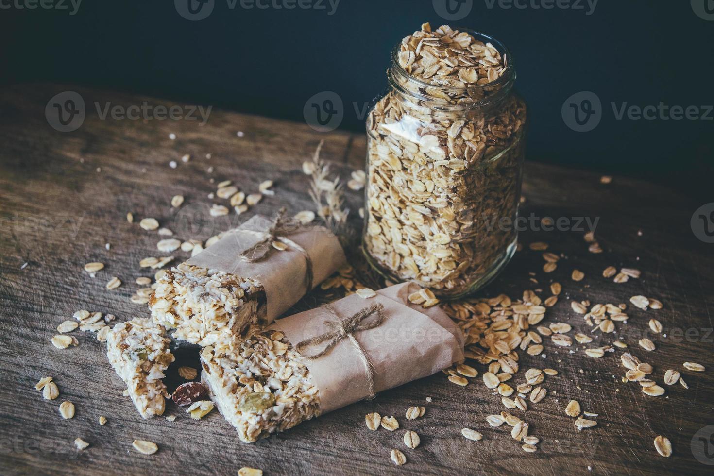 Granola casera con mezcla de nueces en el frasco de vidrio sobre placa de madera foto