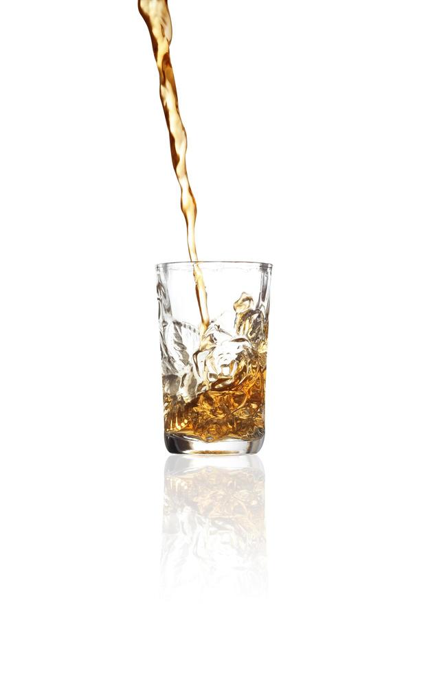 Verter whisky en vaso de chupito sobre fondo blanco. foto