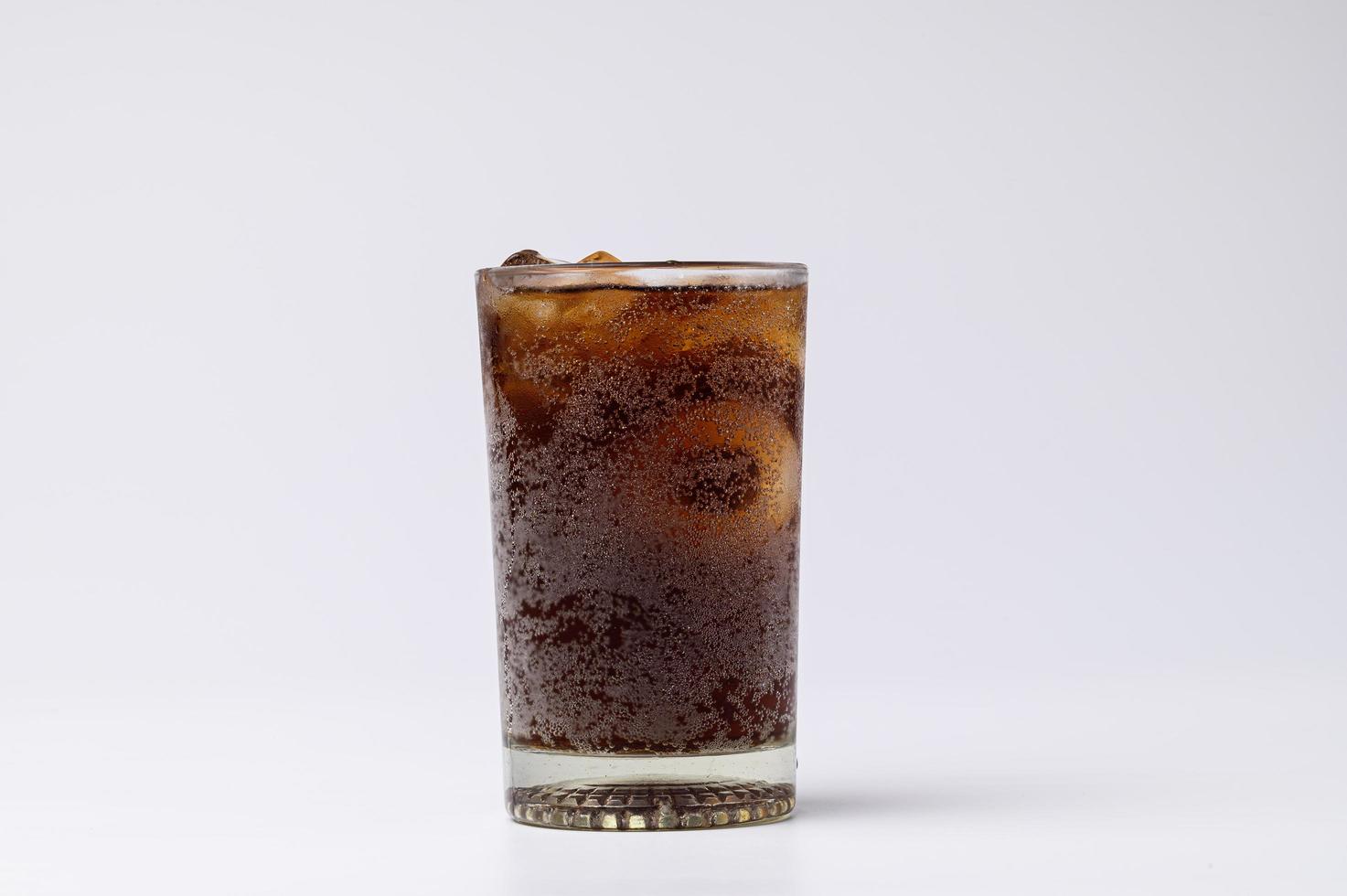 Cola en vaso con cubitos de hielo transparente aislado sobre fondo blanco. foto