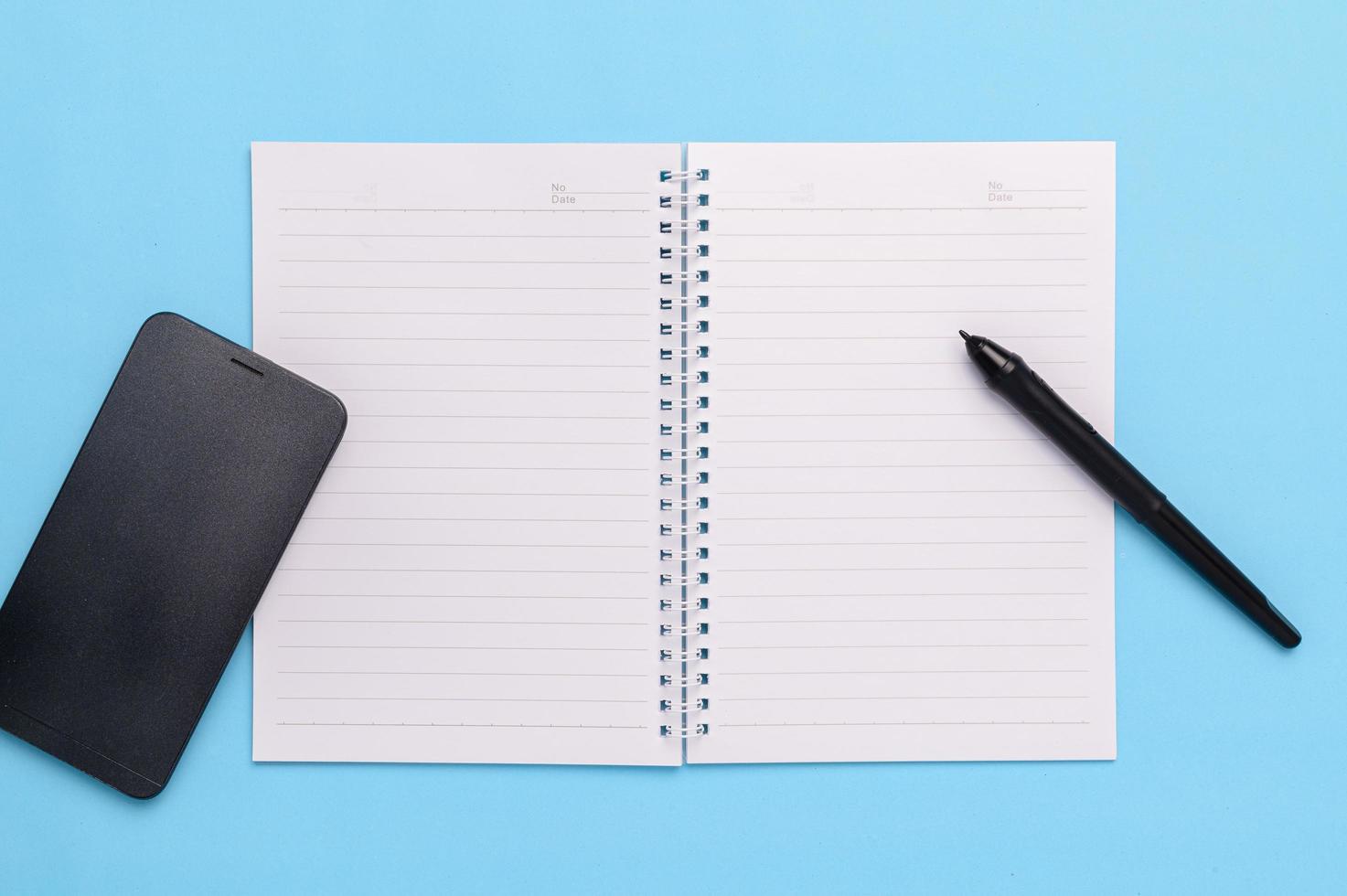 Electronic pen, smartphone, book, coffee mug on a blue background. photo