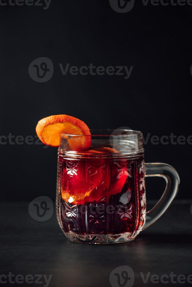 Hot mulled wine in glass cup on dark background photo