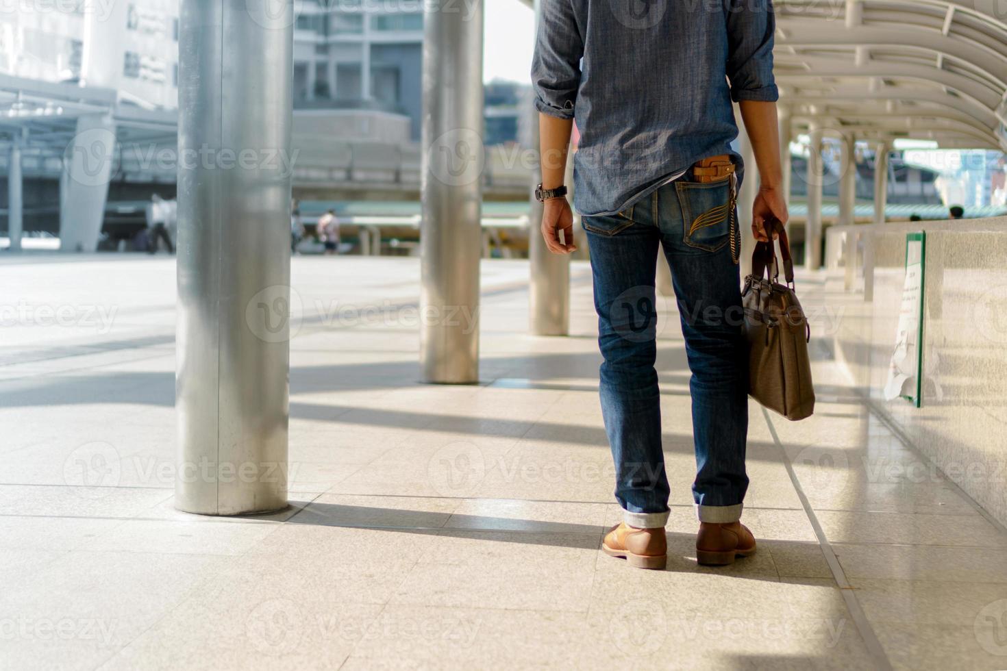 Man walking in the city and holding Laptop bag photo