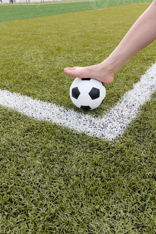 Girl's foot on the soccer ball on green field morning photo