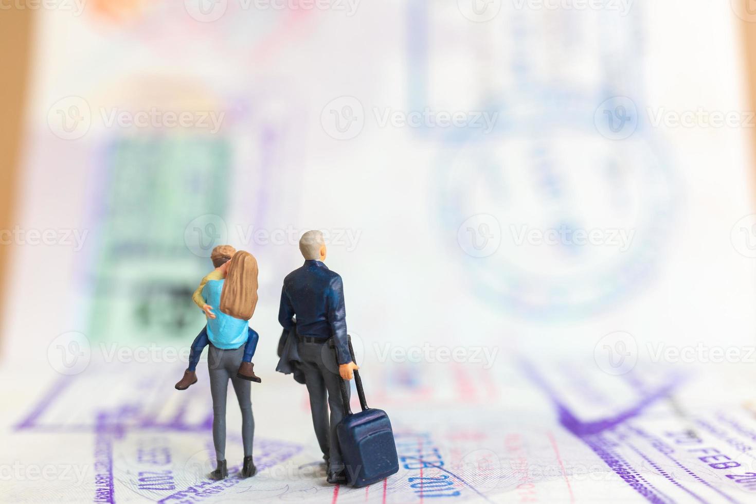 Miniature people couple standing on passport with immigration stamped photo
