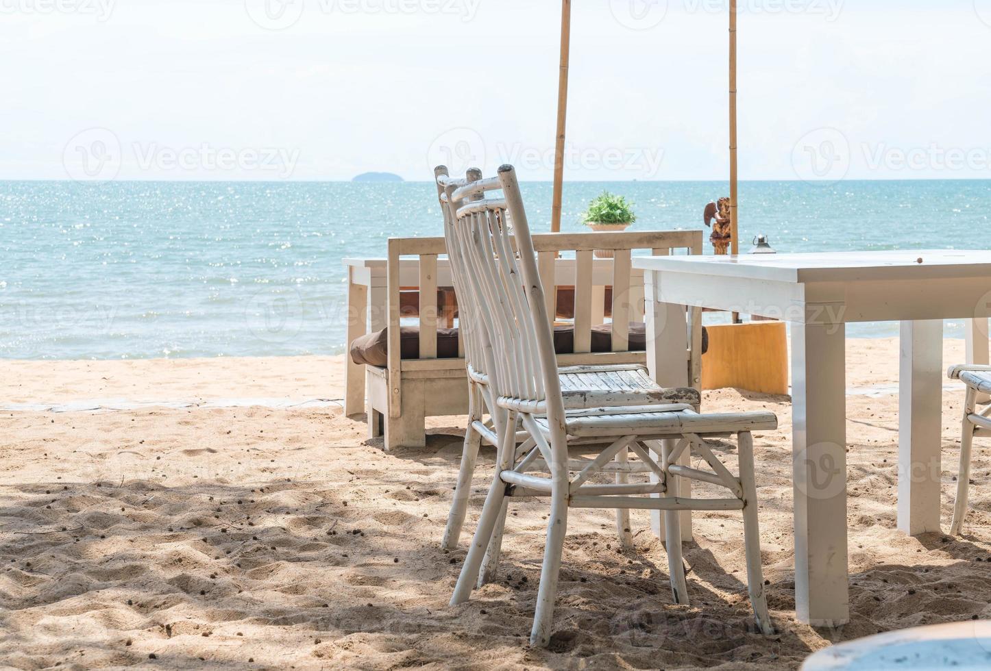 Mesa y sillas blancas en la playa con vistas al océano azul foto