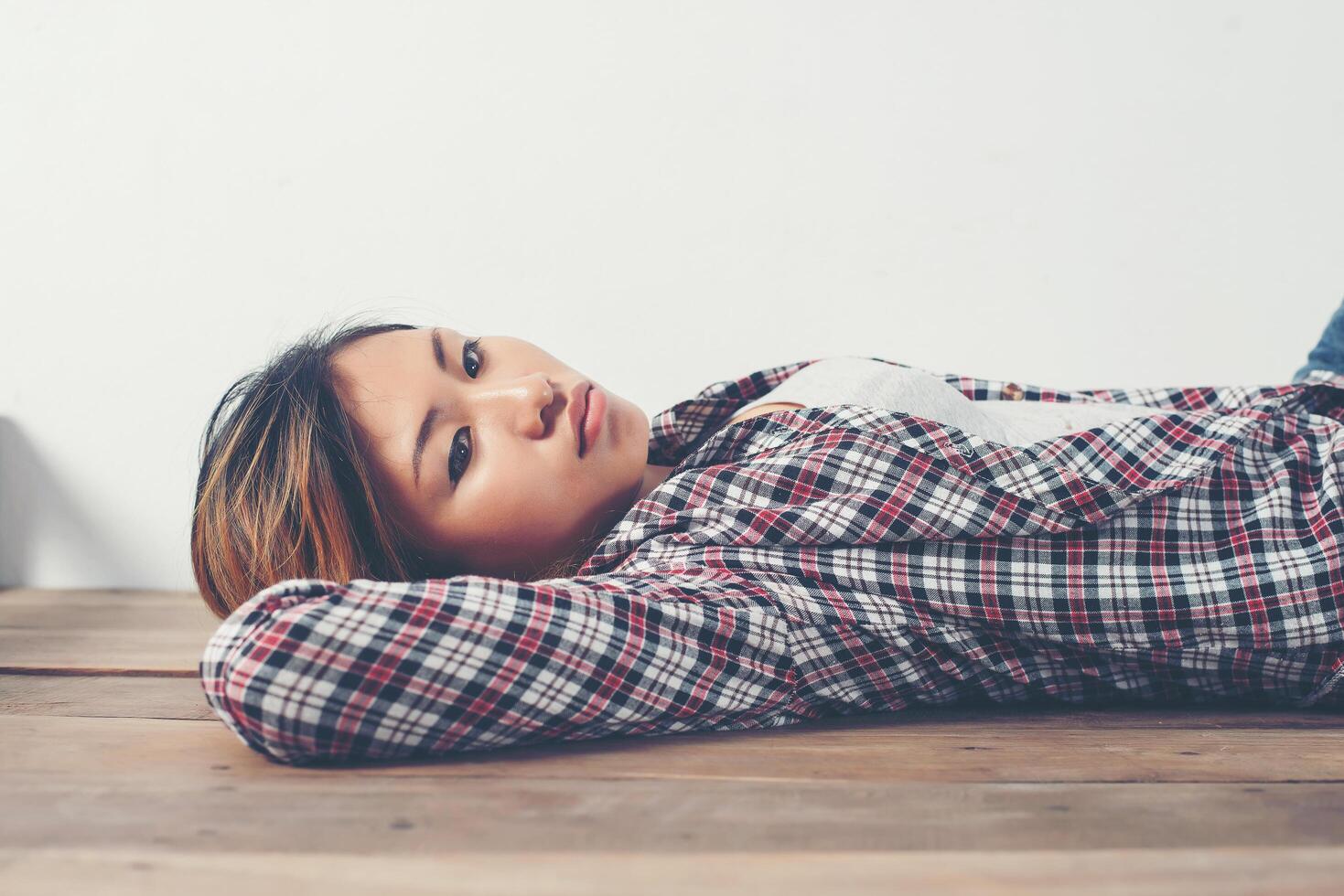 Lonely sad woman deep in thoughts lay down on wooden floor. photo
