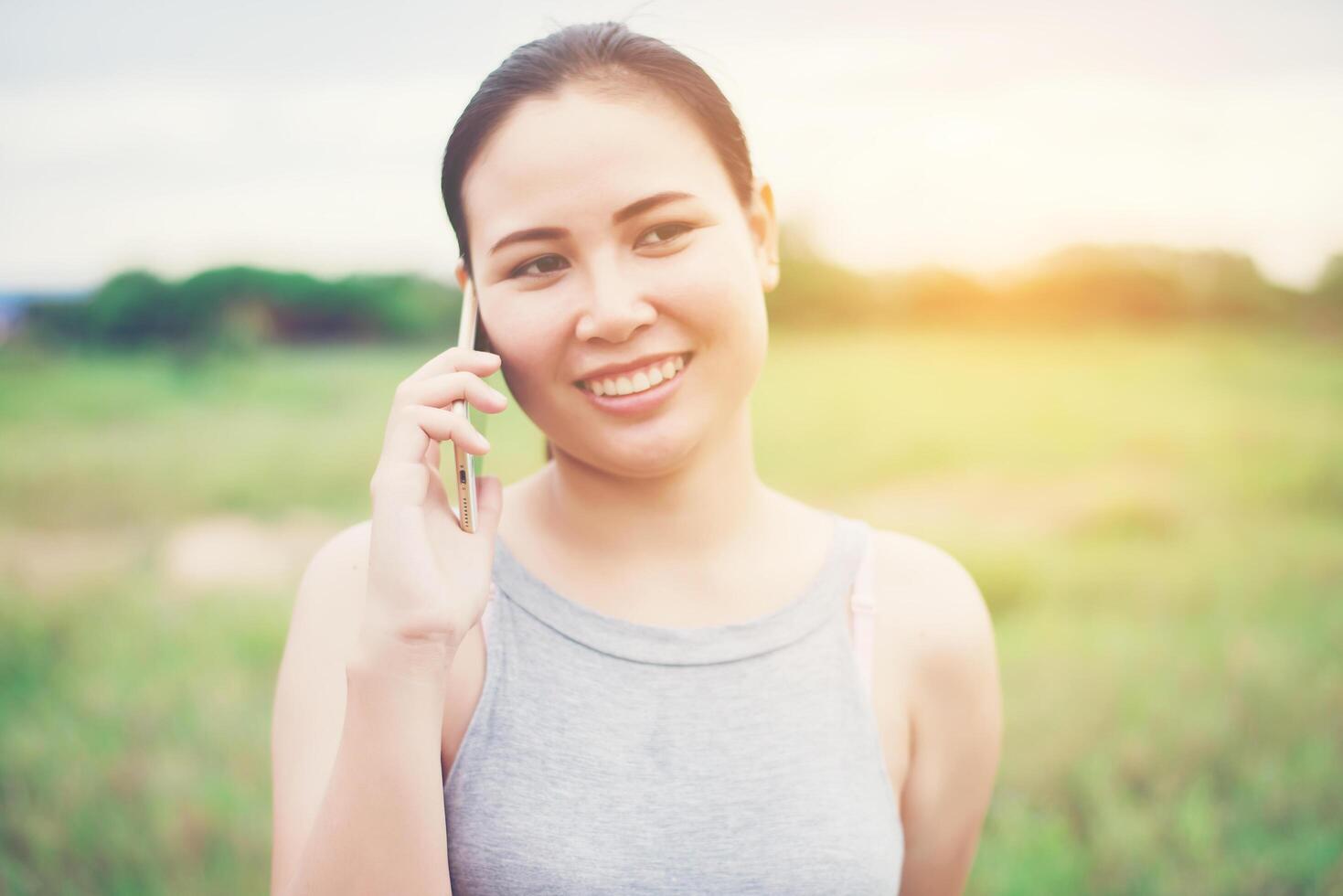 joven y bella mujer con smartphone y sonriendo en el parque. foto