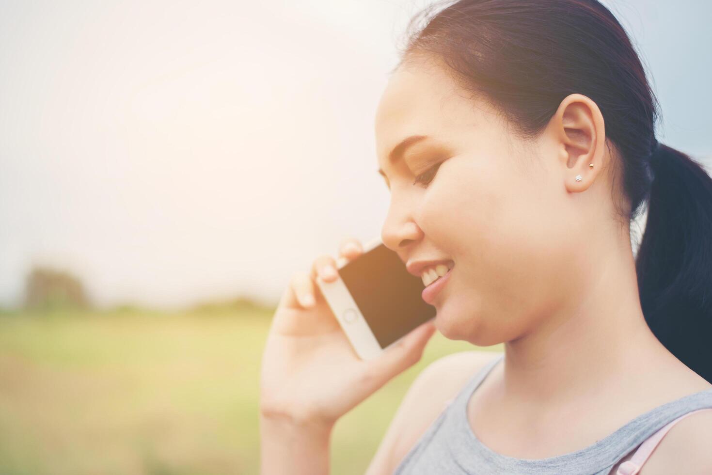 joven y bella mujer con smartphone y sonriendo en el parque. foto