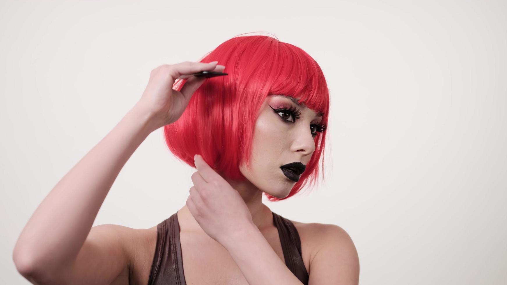 Mujer joven peinando su cabello teñido brillante corto con peine, concepto de cuidado, peinando peluca de pelo rojo, 4k foto