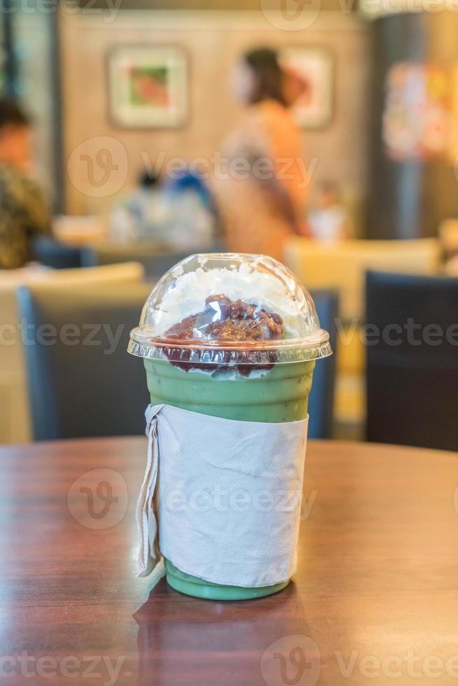 Iced green tea with whipped cream and red bean in cafe photo