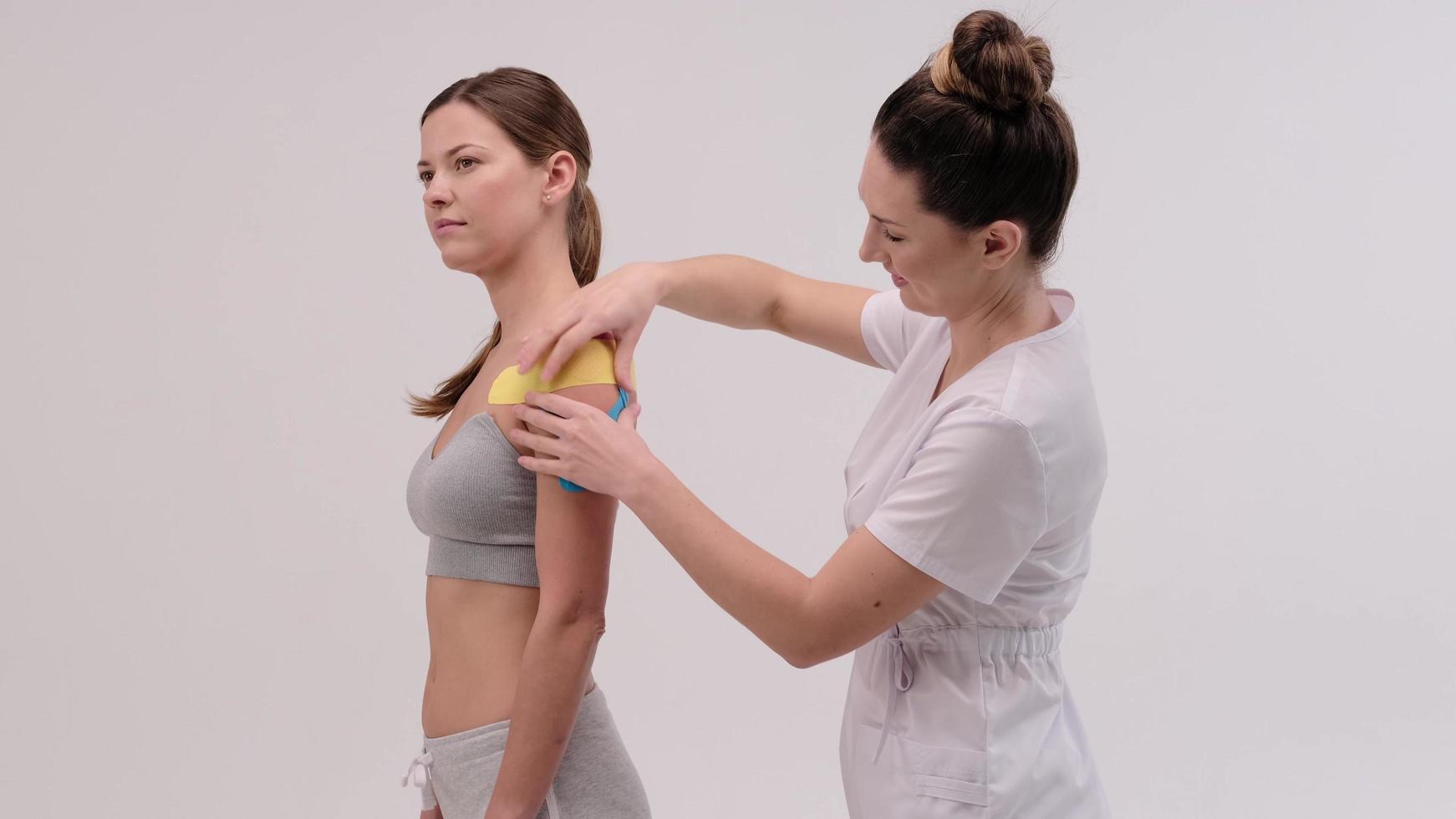 El terapeuta aplica cinta de kinesio al cuerpo femenino. conceptos de fisioterapia y kinesiología. foto