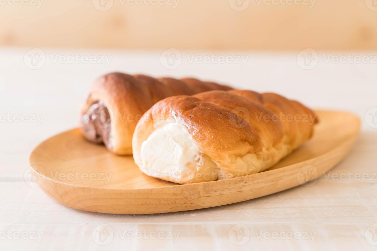 Bread roll with cream on wood plate photo