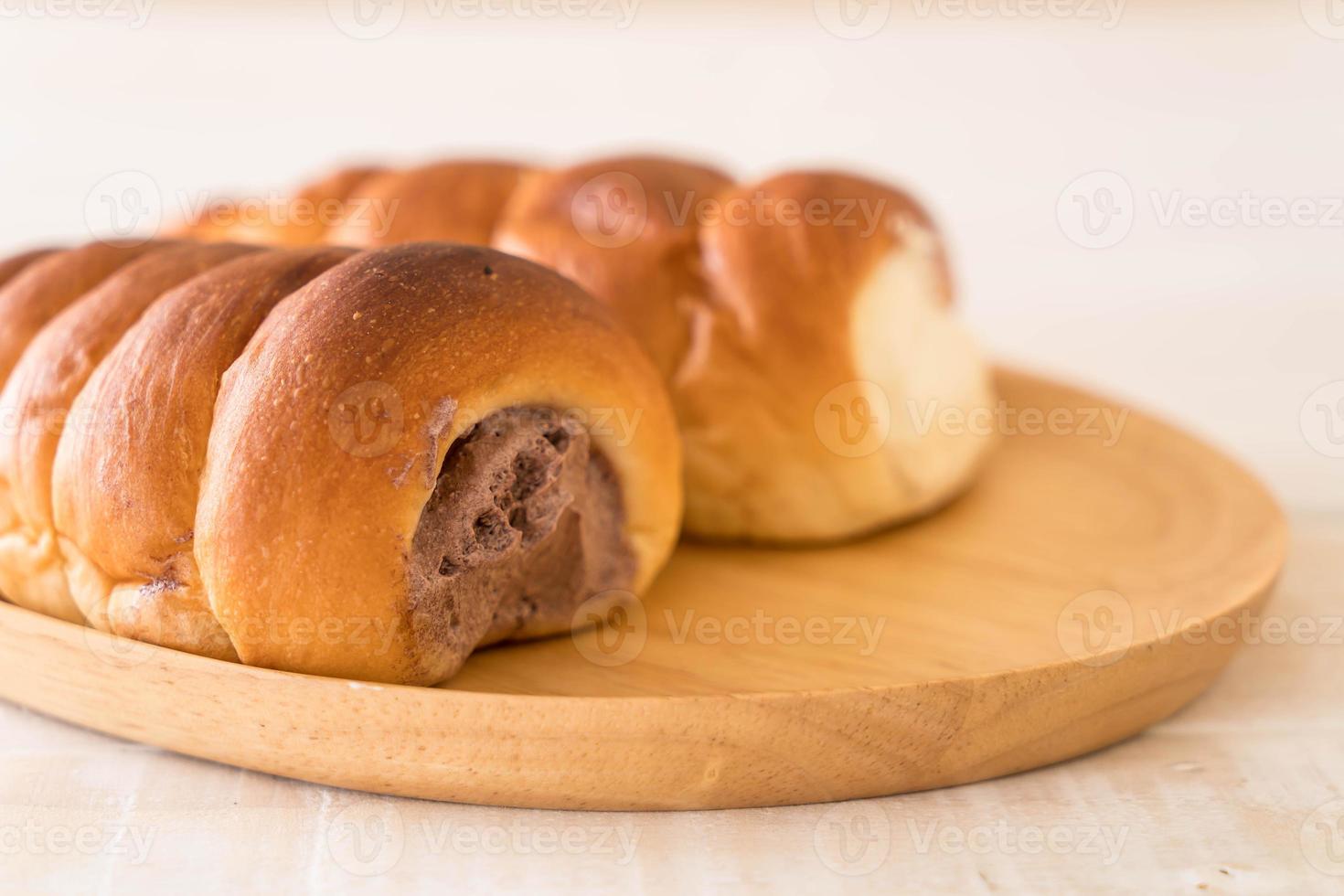 Rollo de pan con crema sobre placa de madera foto