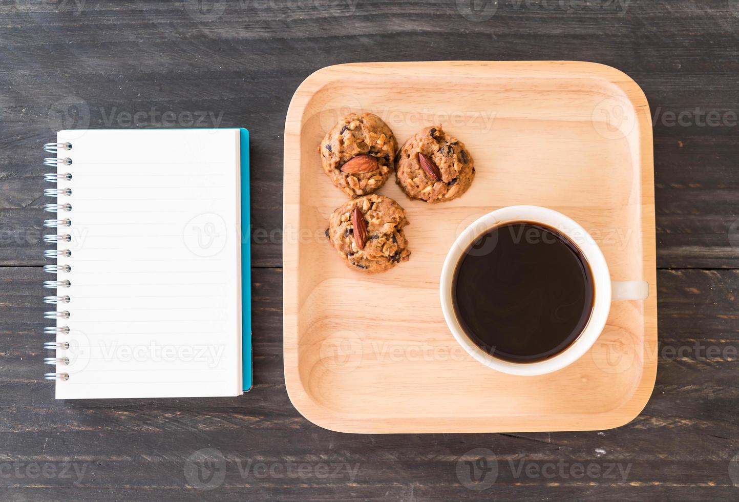 Black coffee and cookies with notebook on table photo