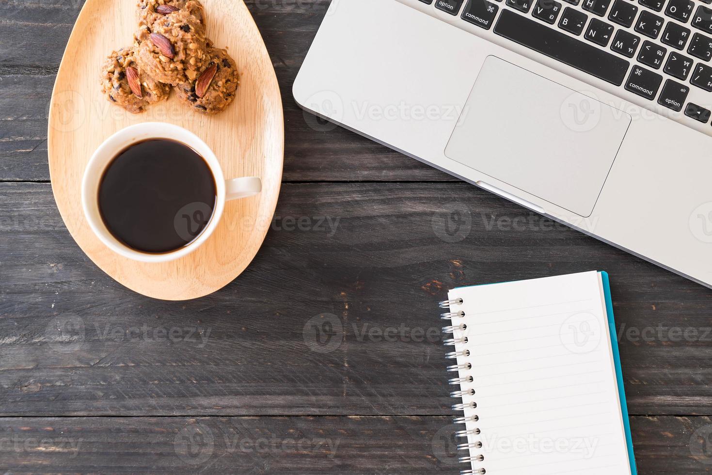 Café negro y galletas con portátil y portátil en la mesa foto