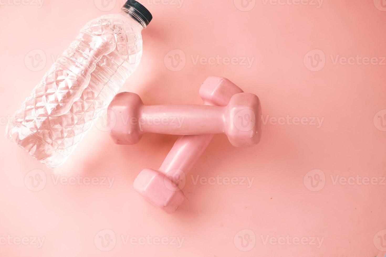 Fitness concept with dumbbell and bottle on white desk. photo