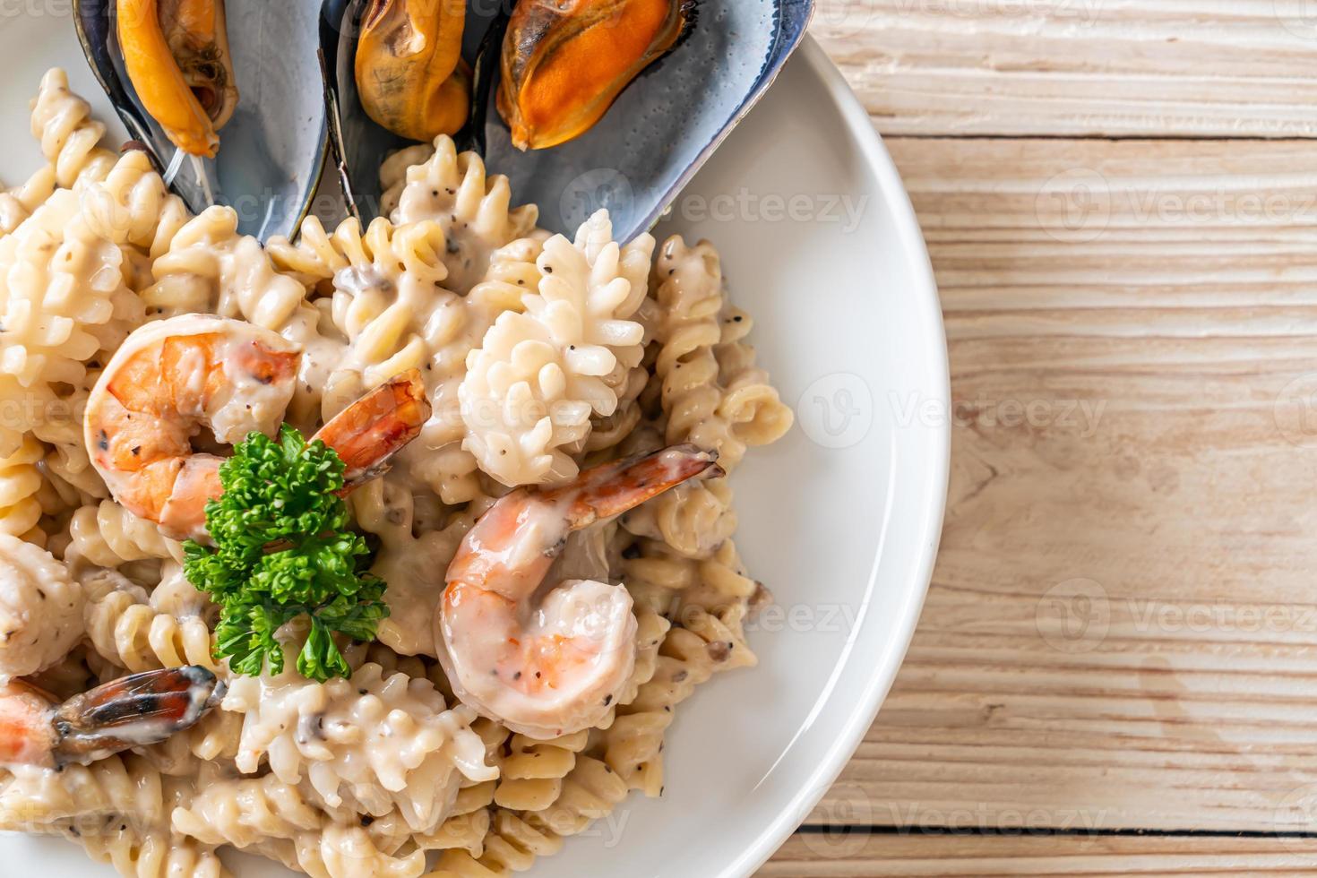 Pasta espiral con salsa de crema de champiñones y mariscos - estilo de comida italiana foto