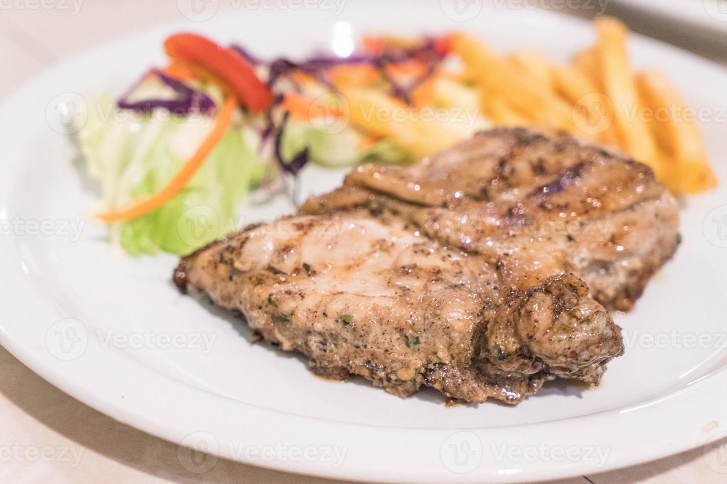 Filete de pollo con pimientos negros en la placa blanca. foto