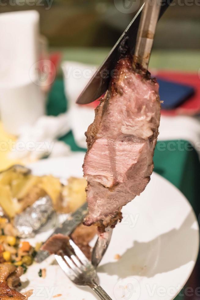 Slicing steak Brazillian style on plate photo