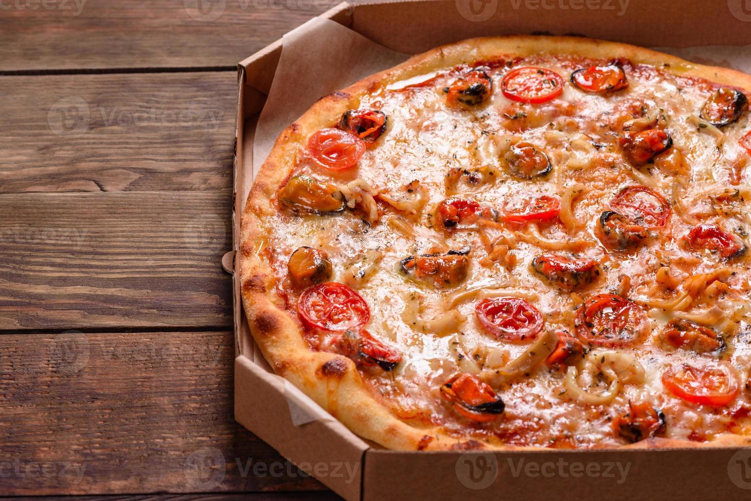 Sabrosa pizza en rodajas con mariscos y tomate sobre un fondo de hormigón foto