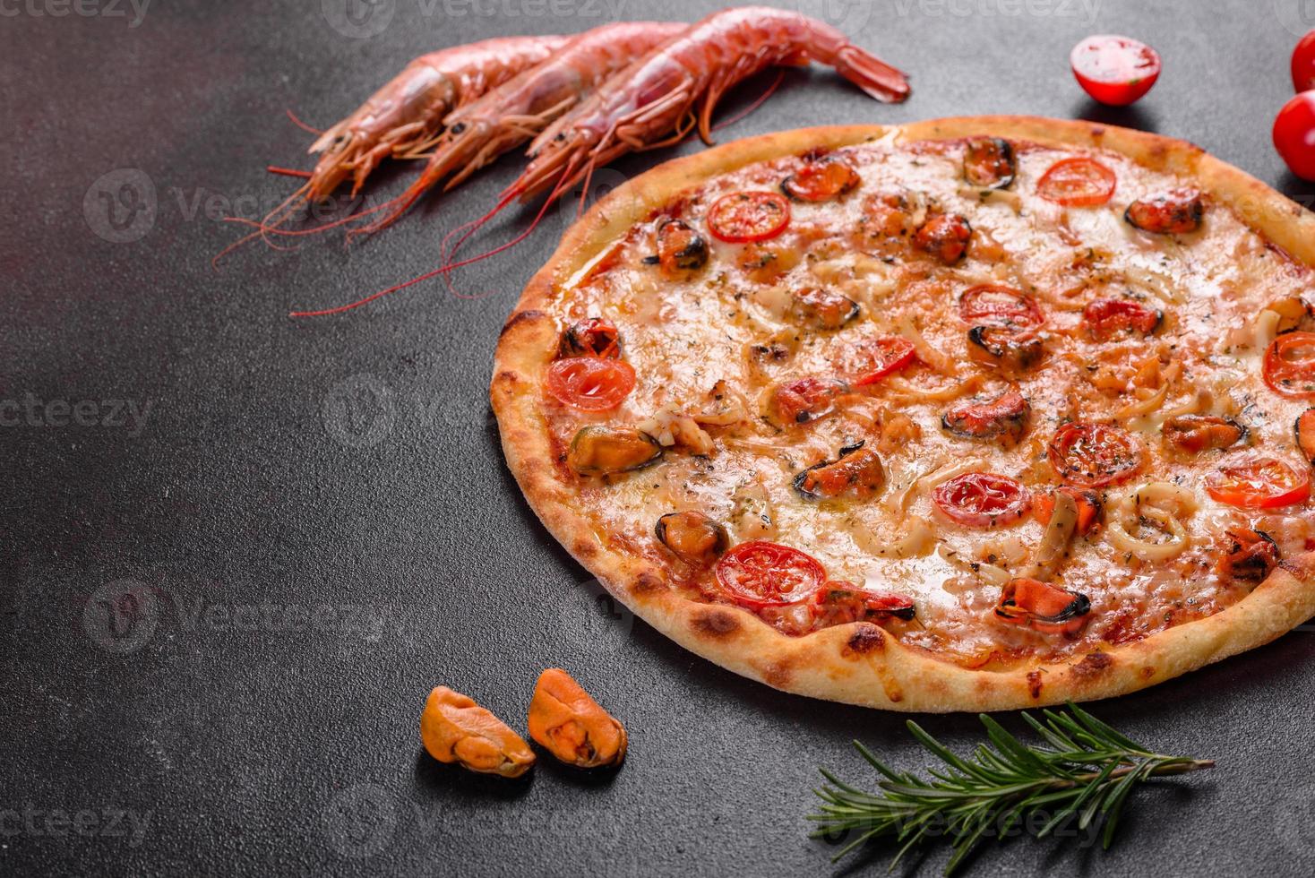 Sabrosa pizza en rodajas con mariscos y tomate sobre un fondo de hormigón foto