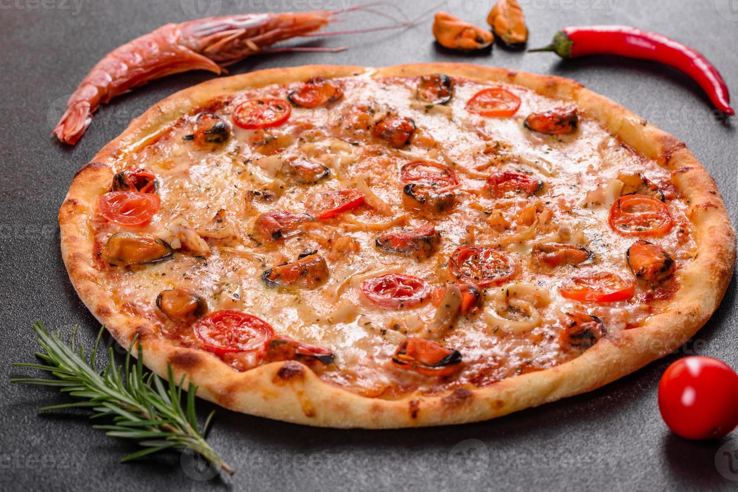 Tasty sliced pizza with seafood and tomato on a concrete background photo