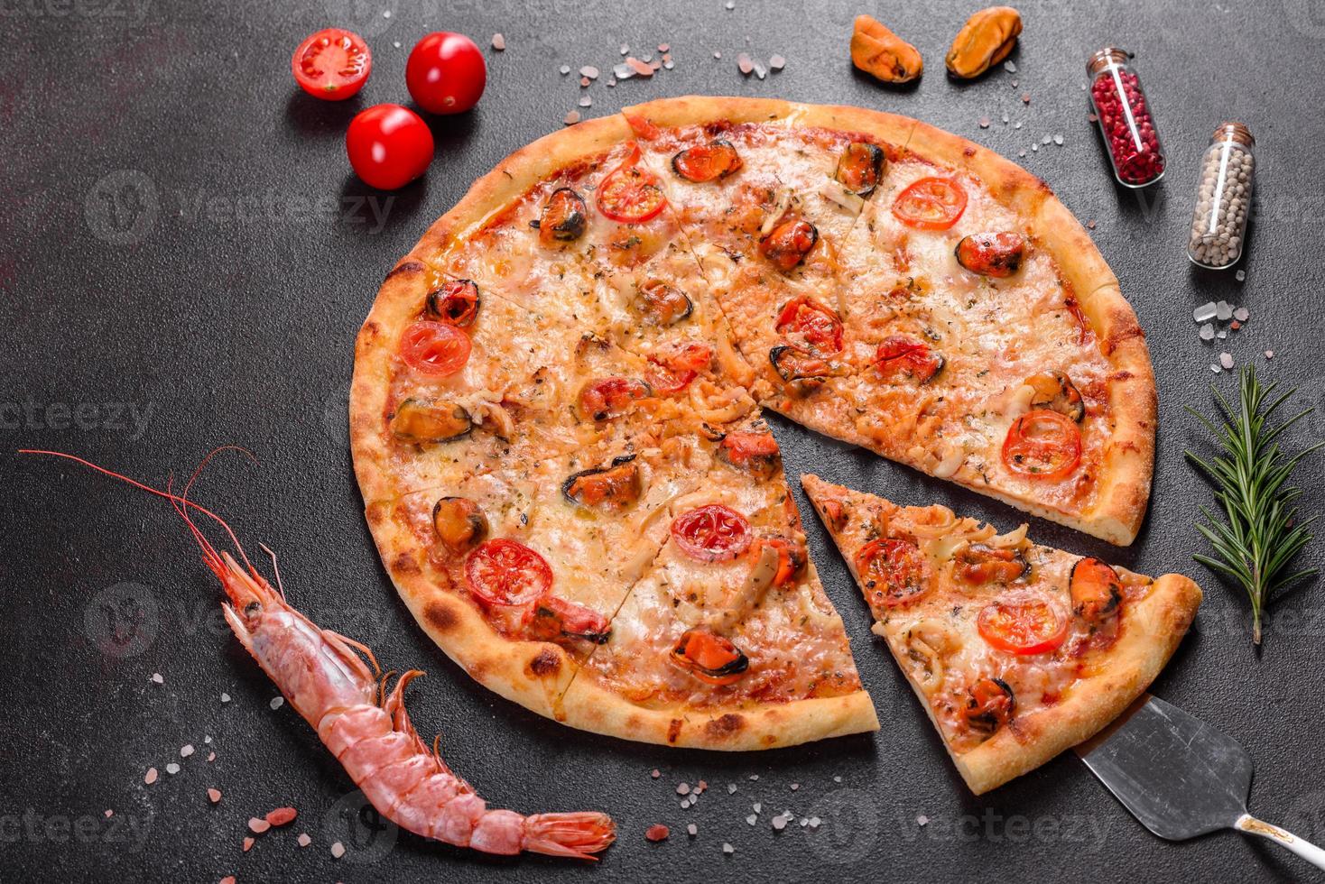 Tasty sliced pizza with seafood and tomato on a concrete background photo