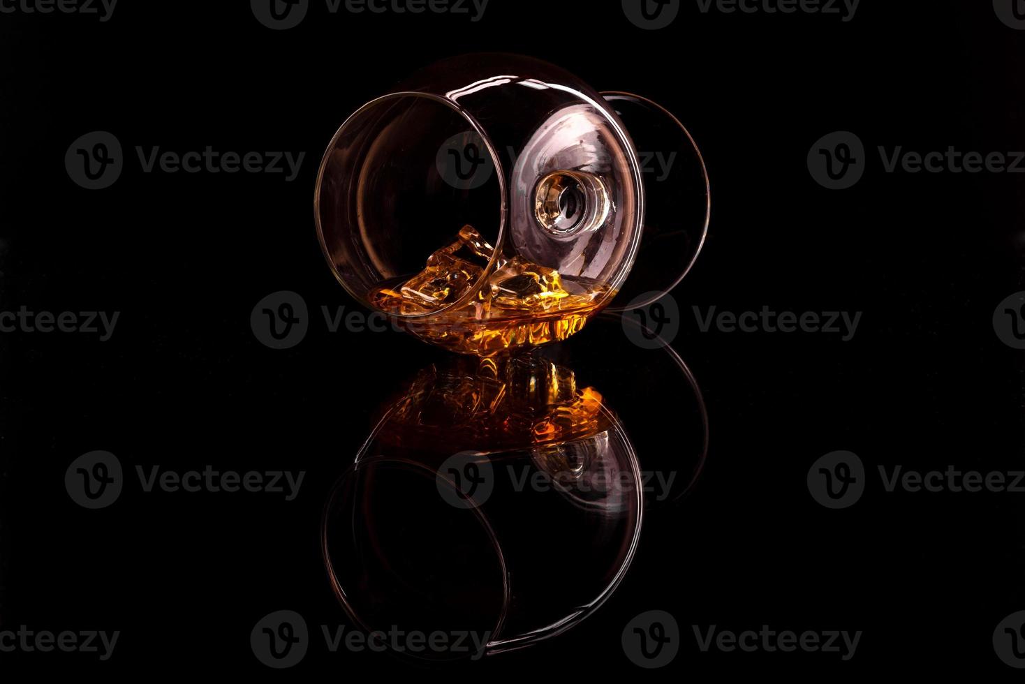 Whiskey with ice in glass isolated on black background photo