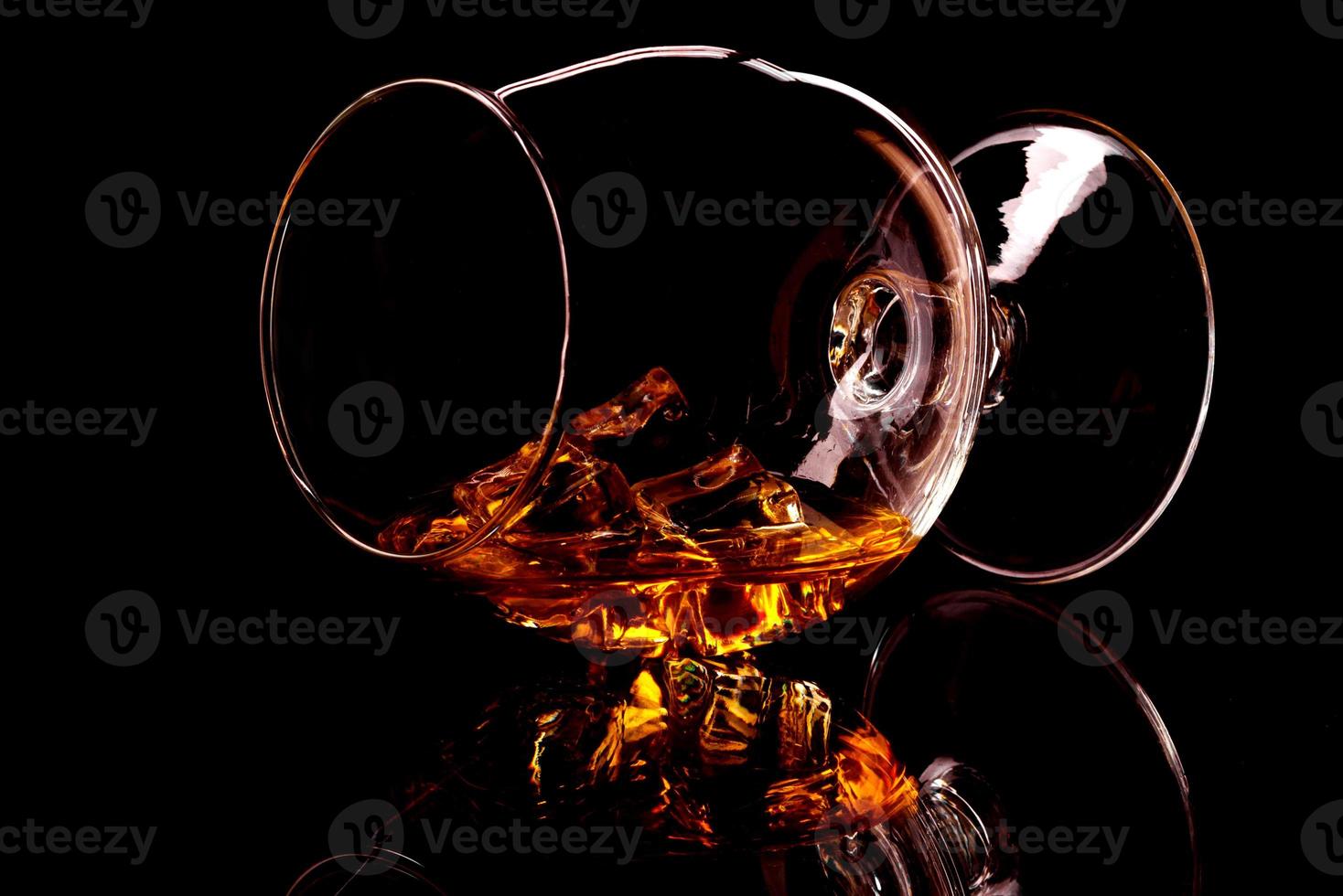 Whiskey with ice in glass isolated on black background photo