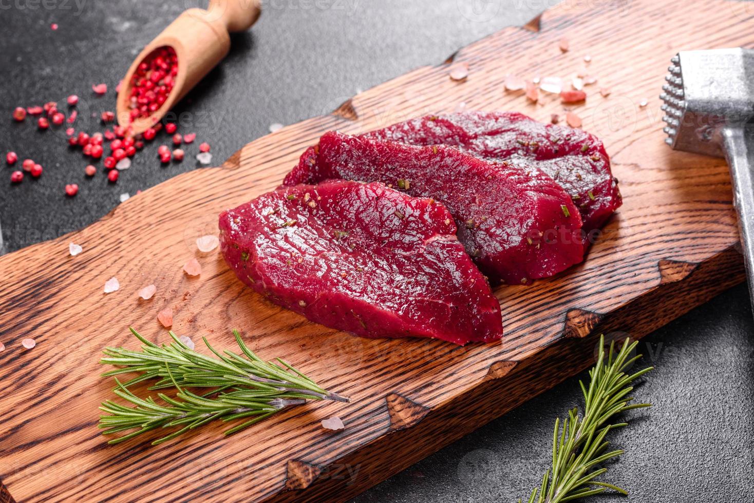 Fresh Raw Beef steak Mignon, with salt, peppercorns, thyme, tomatoes photo