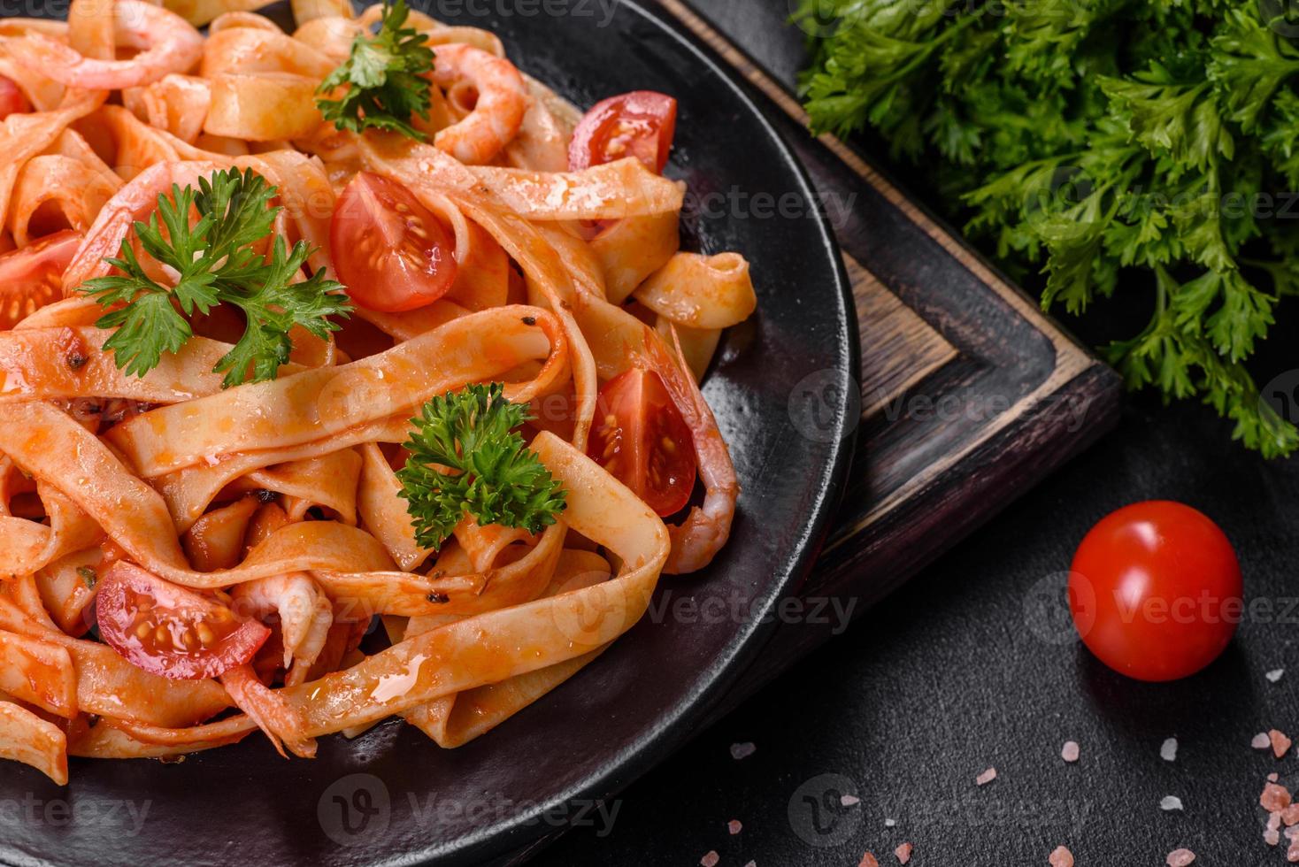 Fettuccine pasta with shrimp, cherry tomatoes, sauce, spices and herbs photo