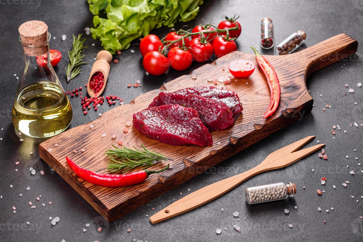 Fresh Raw Beef steak Mignon, with salt, peppercorns, thyme, tomatoes photo