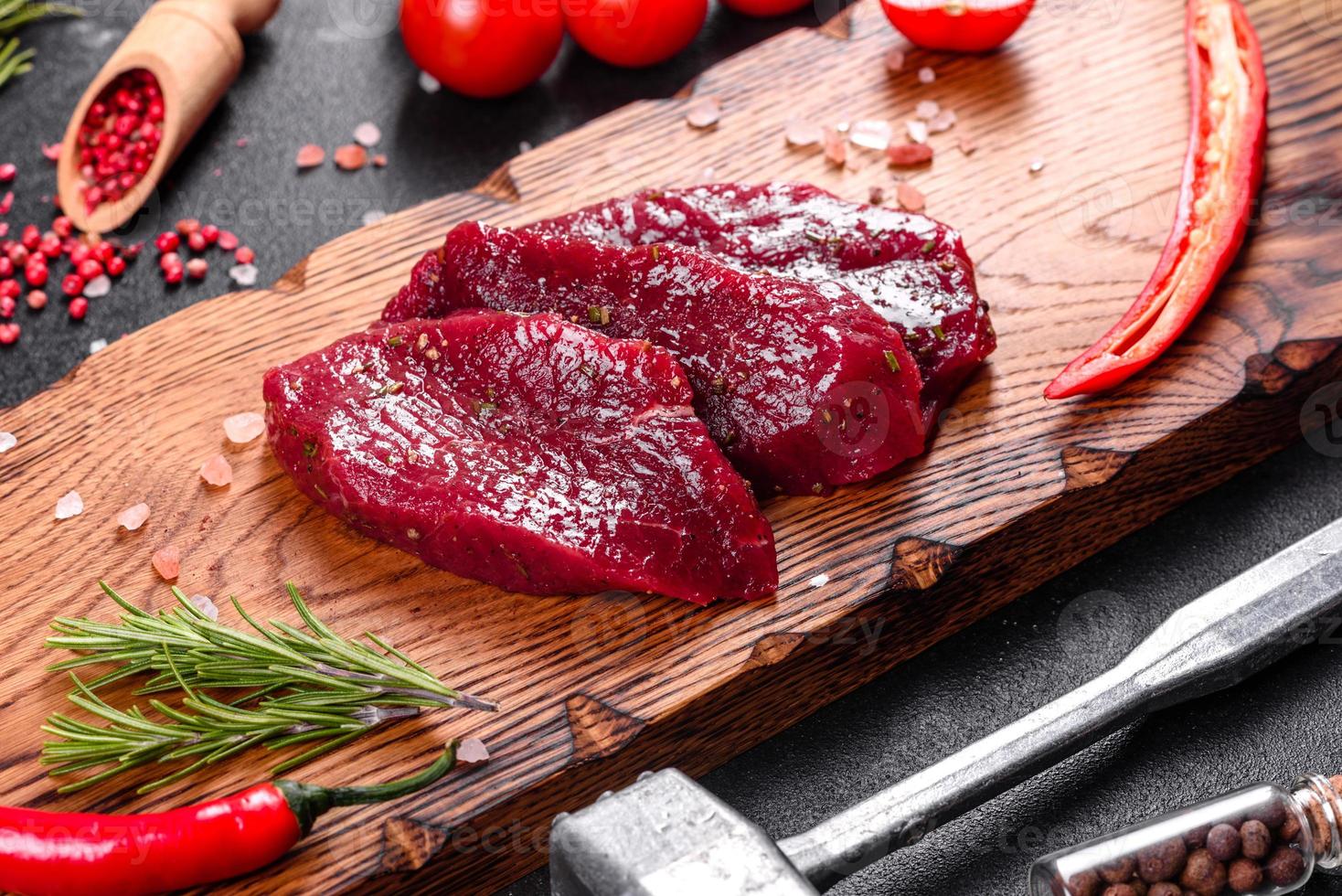 Fresh Raw Beef steak Mignon, with salt, peppercorns, thyme, tomatoes photo