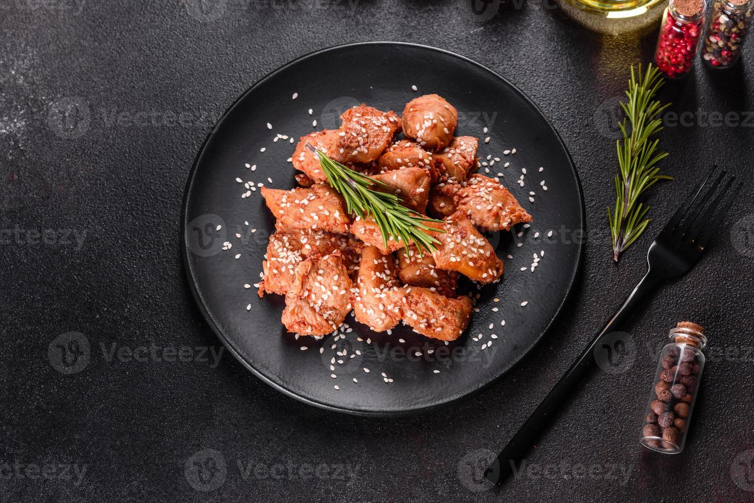 Chicken fillet in sesame seeds, teriyaki sauce on a black stone plate photo