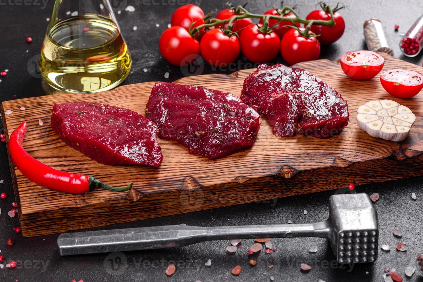 Fresh Raw Beef steak Mignon, with salt, peppercorns, thyme, tomatoes photo