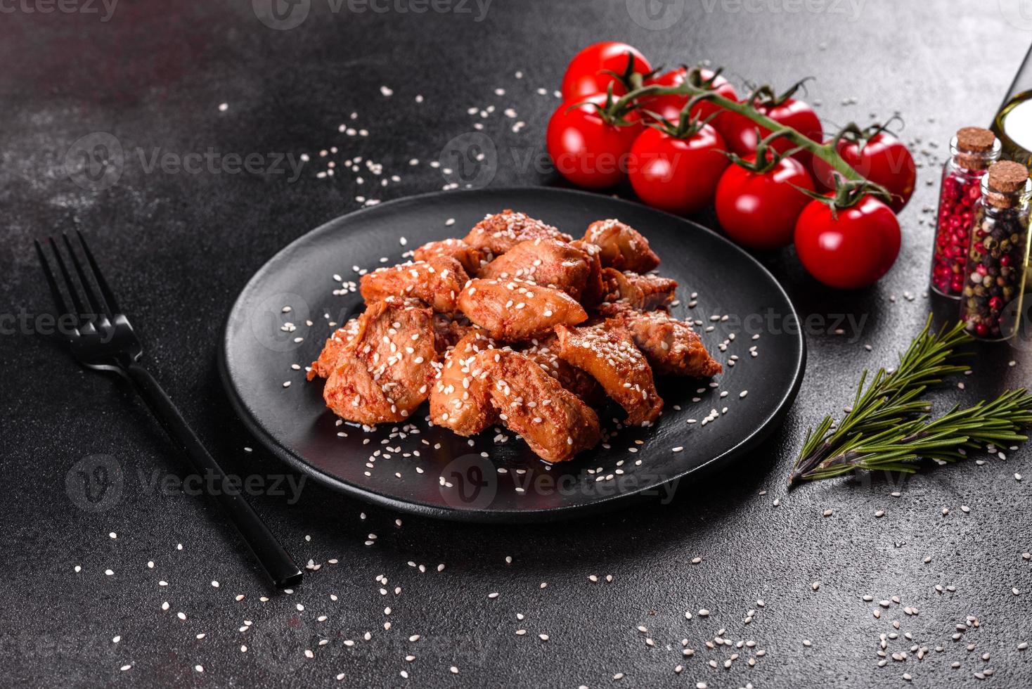 Filete de pollo en ajonjolí, salsa teriyaki sobre plato de piedra negra foto