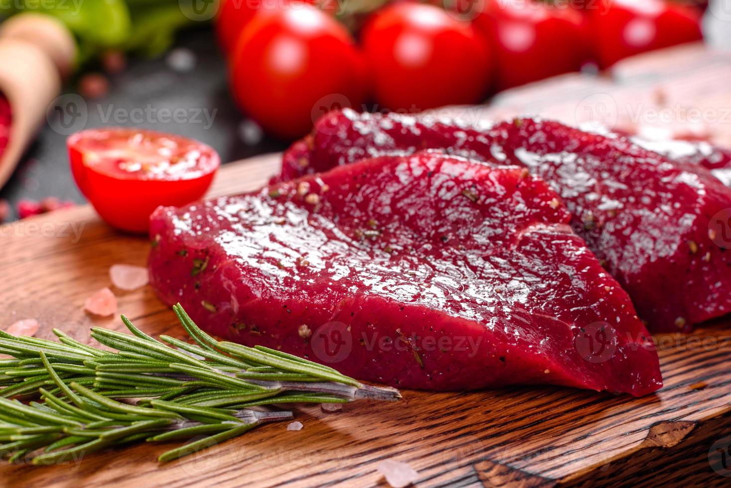 Fresh Raw Beef steak Mignon, with salt, peppercorns, thyme, tomatoes photo