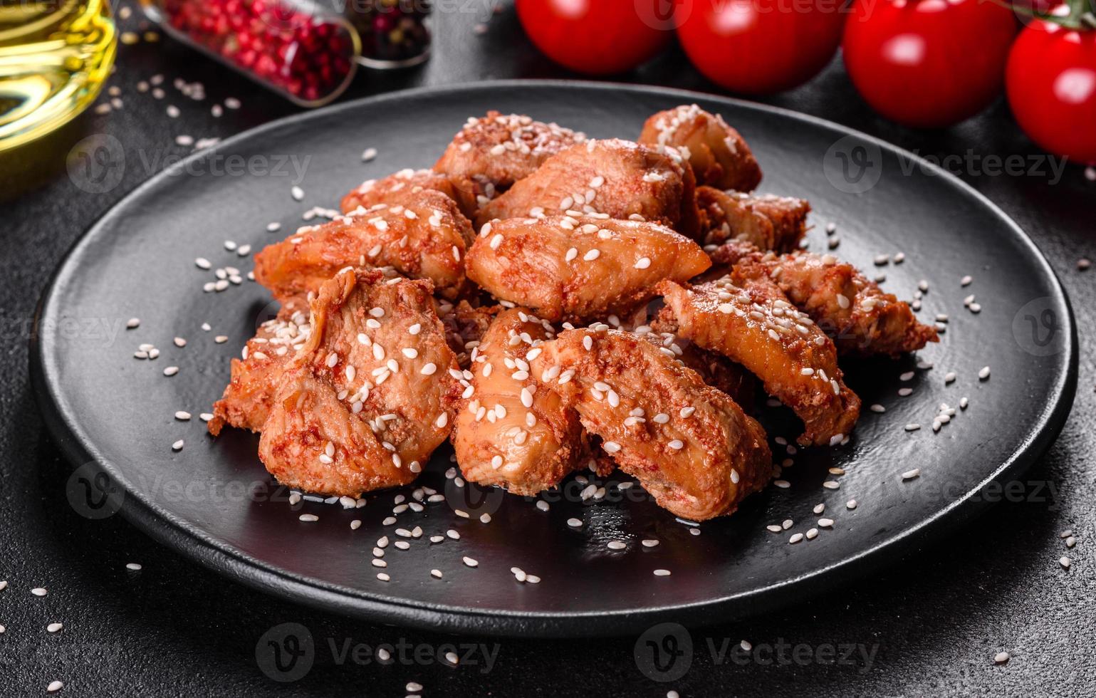 Filete de pollo en ajonjolí, salsa teriyaki sobre plato de piedra negra foto