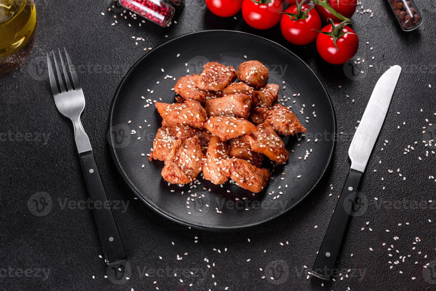 Filete de pollo en ajonjolí, salsa teriyaki sobre plato de piedra negra foto