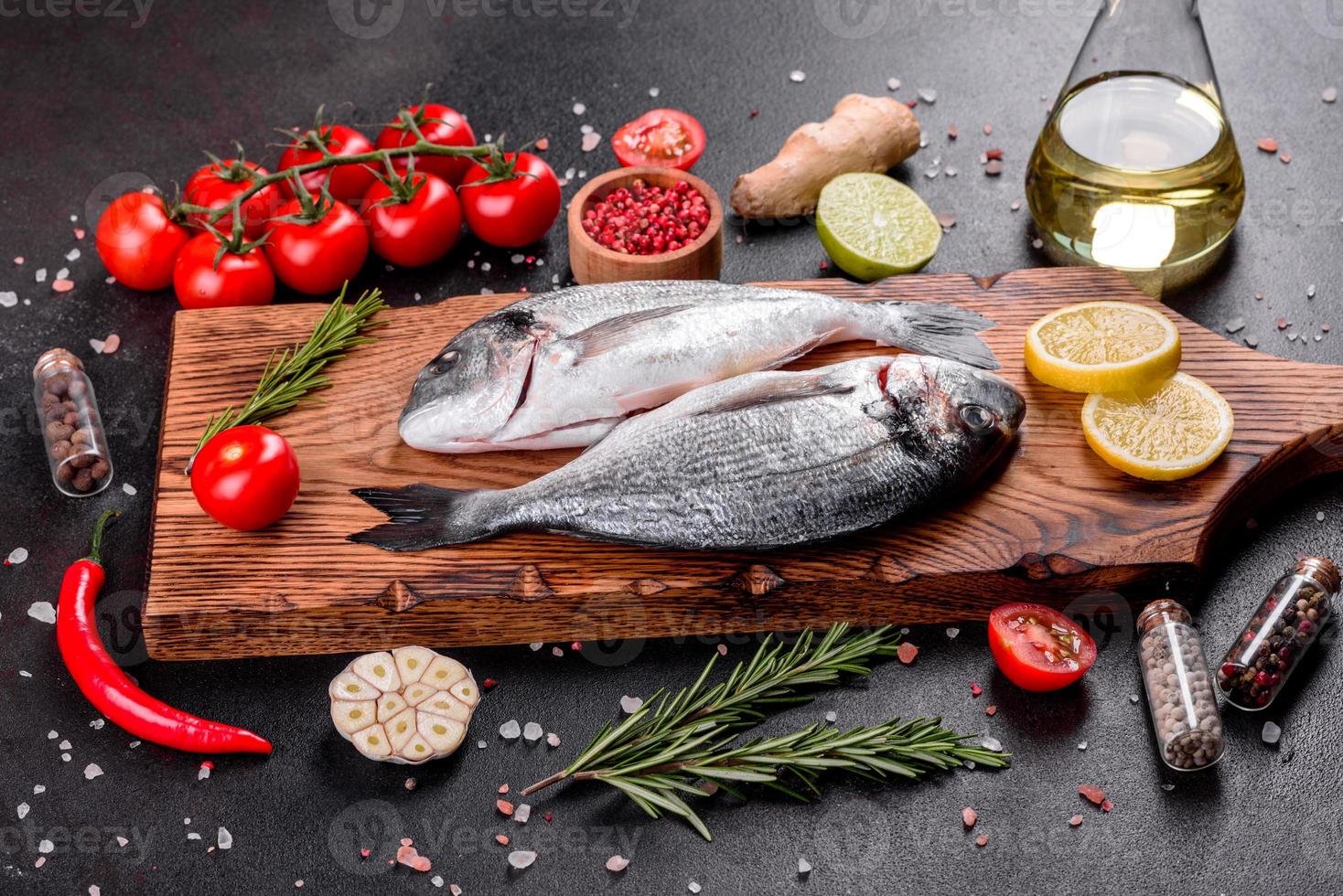 Pescado dorado crudo con especias cocinando sobre tabla de cortar foto