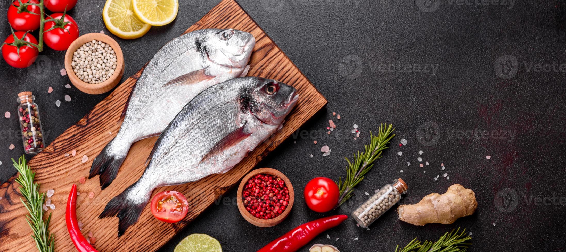 Pescado dorado crudo con especias cocinando sobre tabla de cortar foto