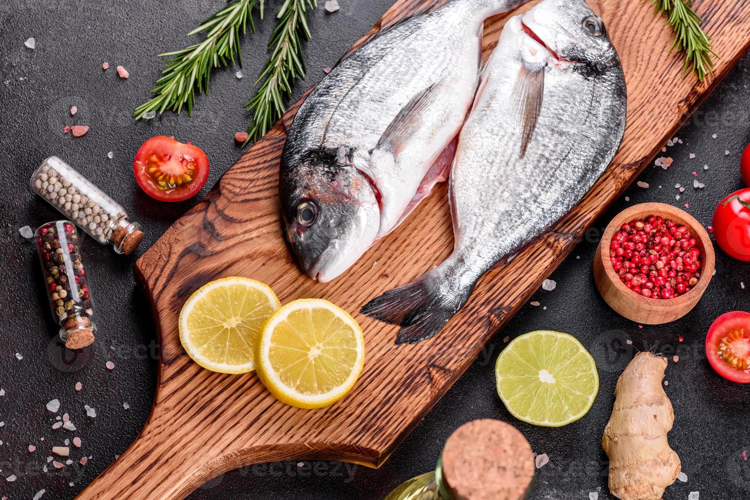 Pescado dorado crudo con especias cocinando sobre tabla de cortar foto