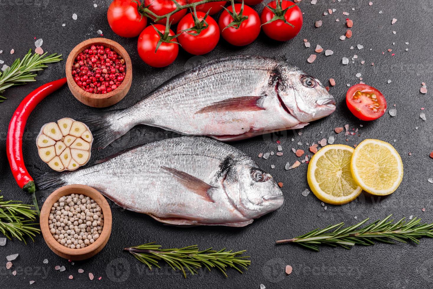 Pescado dorado crudo con especias cocinando sobre tabla de cortar foto