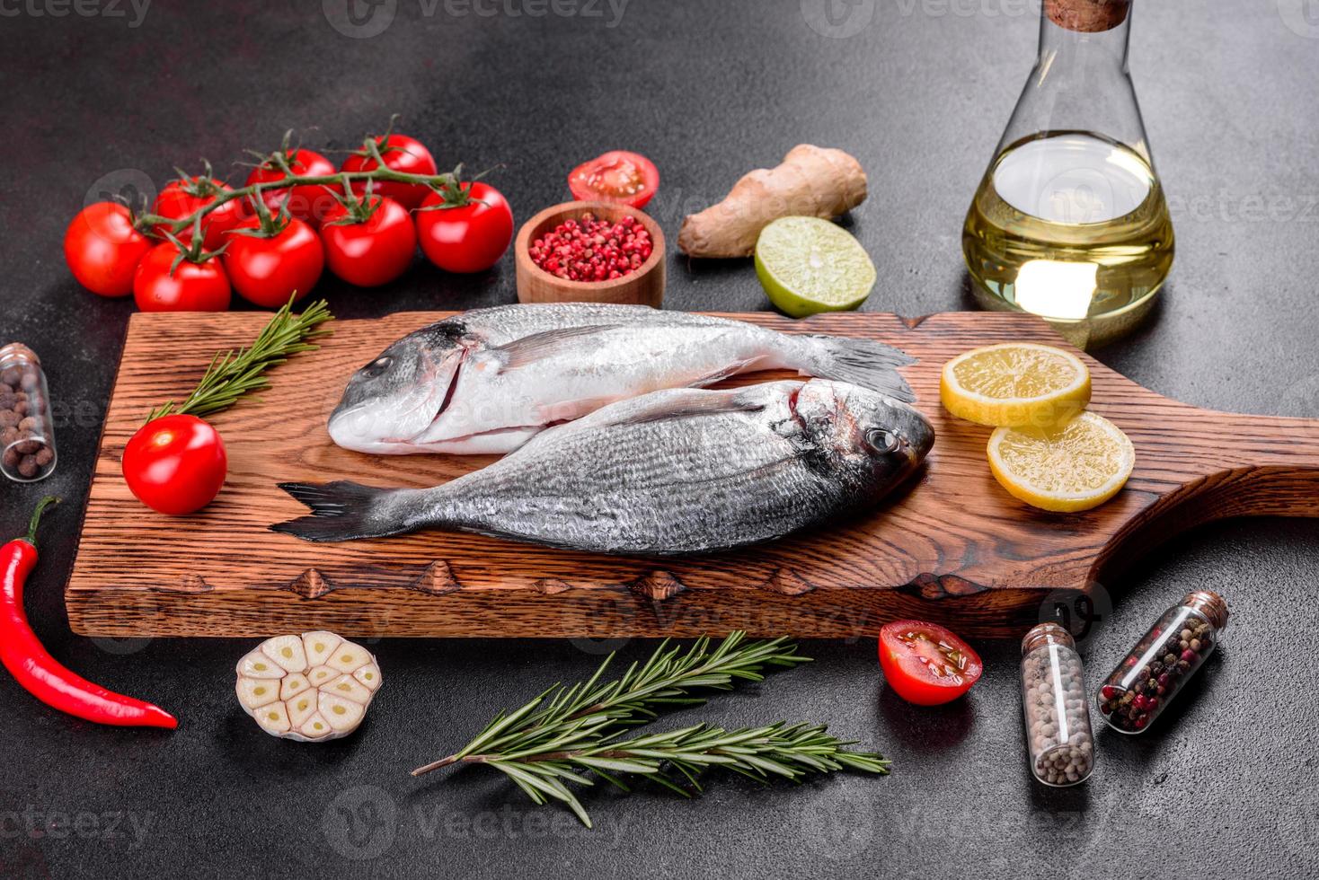 Pescado dorado crudo con especias cocinando sobre tabla de cortar foto