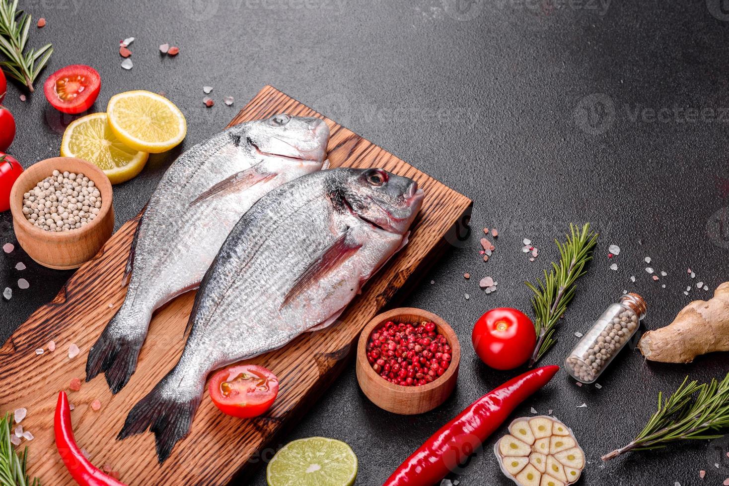 Pescado dorado crudo con especias cocinando sobre tabla de cortar foto