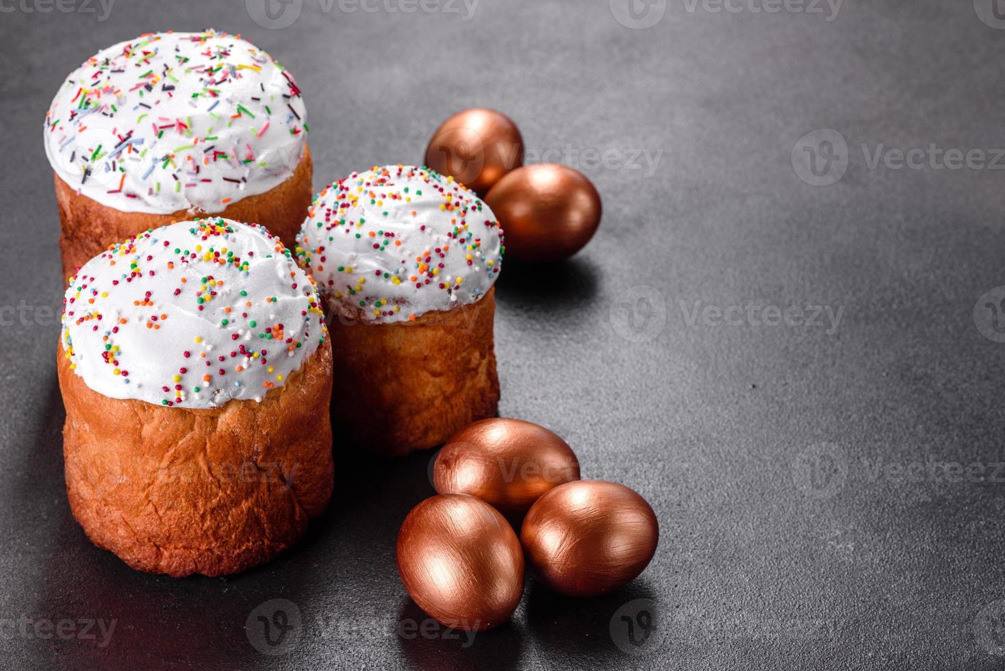 Huevos de pascua de oro y bronce y pastel de pascua sobre un fondo oscuro foto